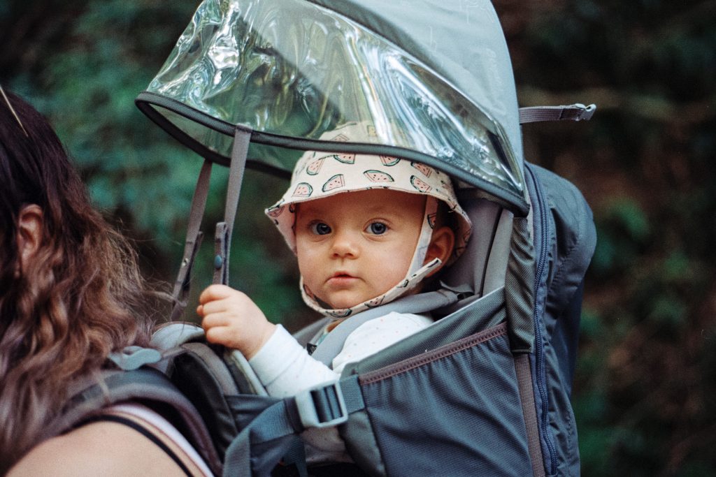 Un béb avec un chapeau dans un porte bébé de randonnée