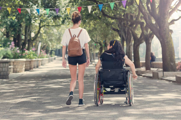 Jeune femme qui marche à côté de son amie en fauteuil roulant