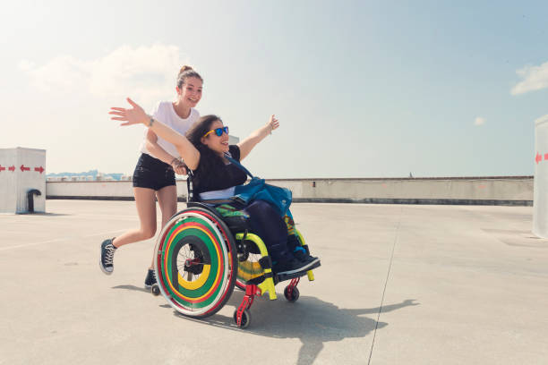 Jeune femme qui pousse le fauteuil roulant de son amie